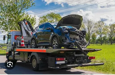 Accident-damaged red car securely strapped onto a flatbed transport truck demonstrating How Can a Car Towing Service Help You After an Accident?