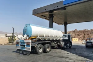 A large commercial tanker truck parked at a gas station station for Fuel Delivery services